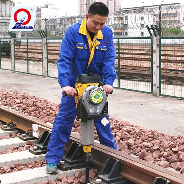 Close-up of a hydraulic rail tamping machine compacting ballast under sleepers Close-up of a hydraulic rail tamping machine compacting ballast under sleepers